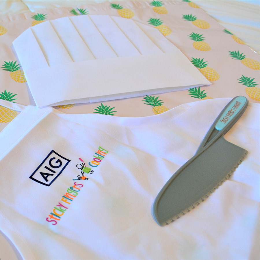 custom apron, a chef hat, and a kid-friendly knife provided by sticky fingers cooking