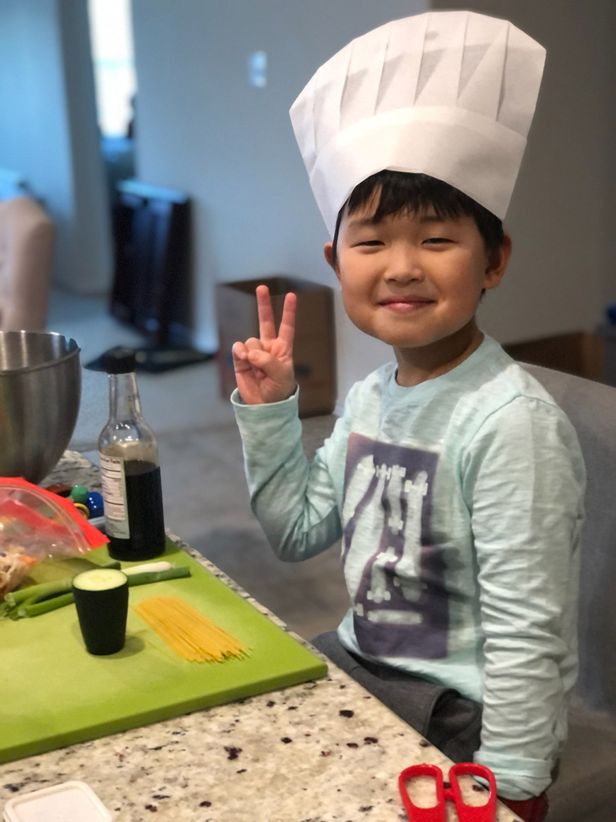 boy doing a peace sign with his fingers during a sticky fingers cooking online birthday party